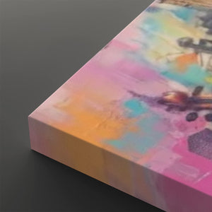 A close-up of a rectangular canvas print showing an abstract watercolor-style design with blended pink, yellow, blue, and orange tones, photographed on a dark gray background.