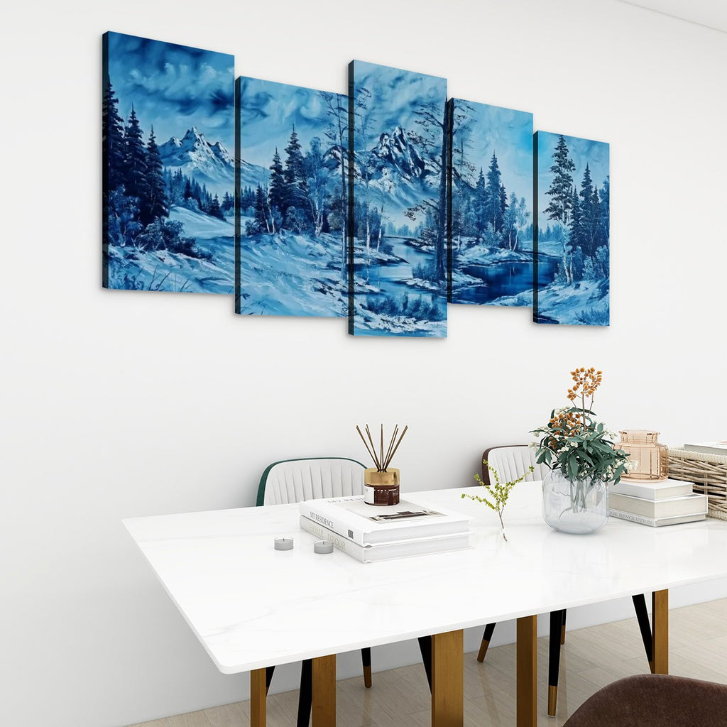 A five-panel canvas wall art set depicting a snowy mountain landscape in shades of blue, hung on a white wall above a modern white dining table with chairs and decorative items.