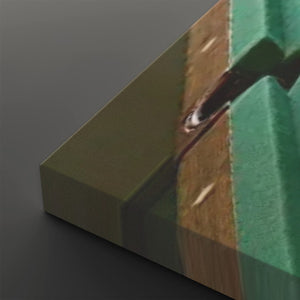 A close-up of a rectangular panel or block showing a printed scene with green, brown, and dark tones, photographed against a dark gray background.