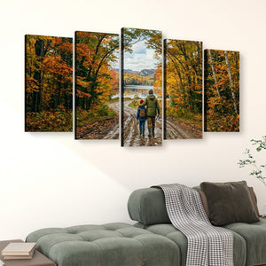 A five-panel canvas wall art set depicting a couple walking along a dirt path surrounded by colorful autumn trees near a lake, displayed above a green sofa in a living room setting.