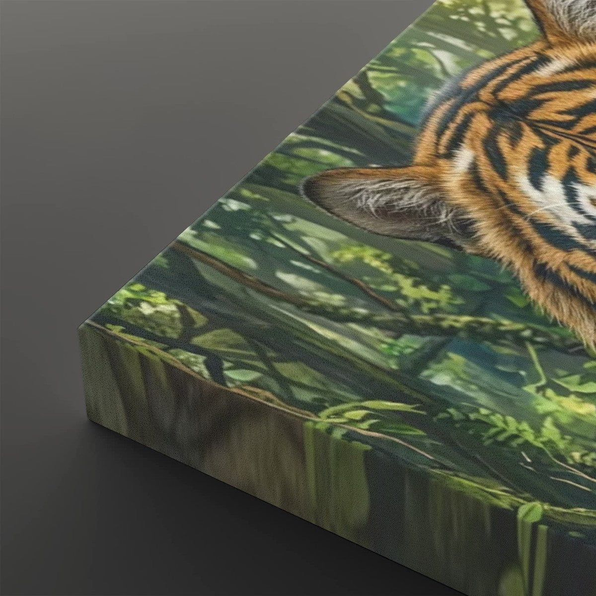 A close-up of a rectangular canvas or print showing part of a tiger's face and body over a lush green forest scene, photographed against a dark gray background.
