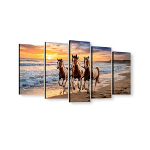 A five-panel canvas wall art set depicting three horses running along a sandy beach at sunset, shown against a plain white background.