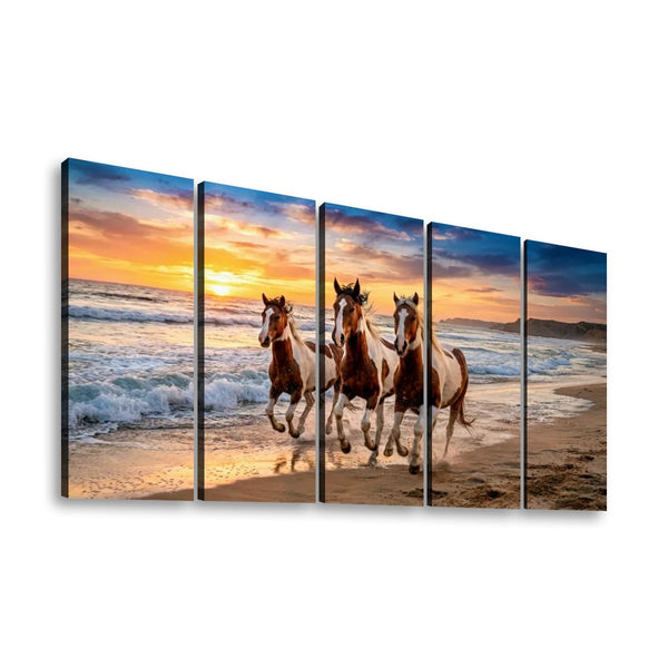 A five-panel canvas wall art print depicting three horses running through ocean waves at sunset on a sandy beach, shown against a plain white background.