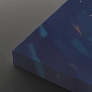 A close-up of a rectangular canvas or panel with a dark blue abstract print, showing its side edge and corner against a neutral gray background.