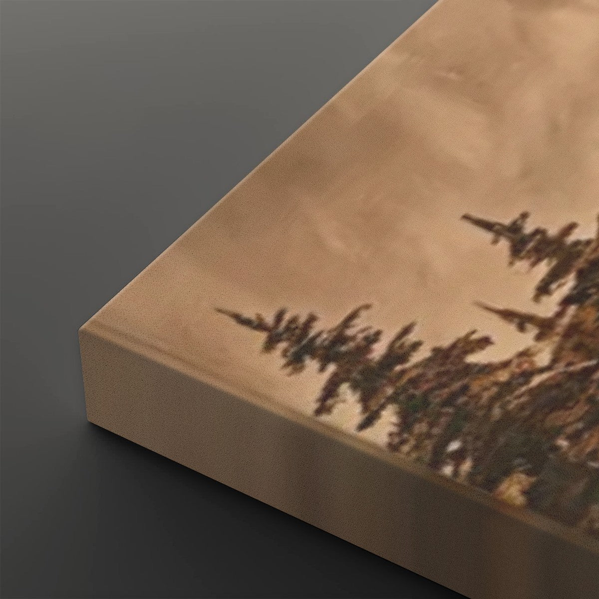 A close-up of a rectangular canvas or panel with a warm beige/tan surface and a dark tree-like abstract print along one edge, shown against a dark gray background.