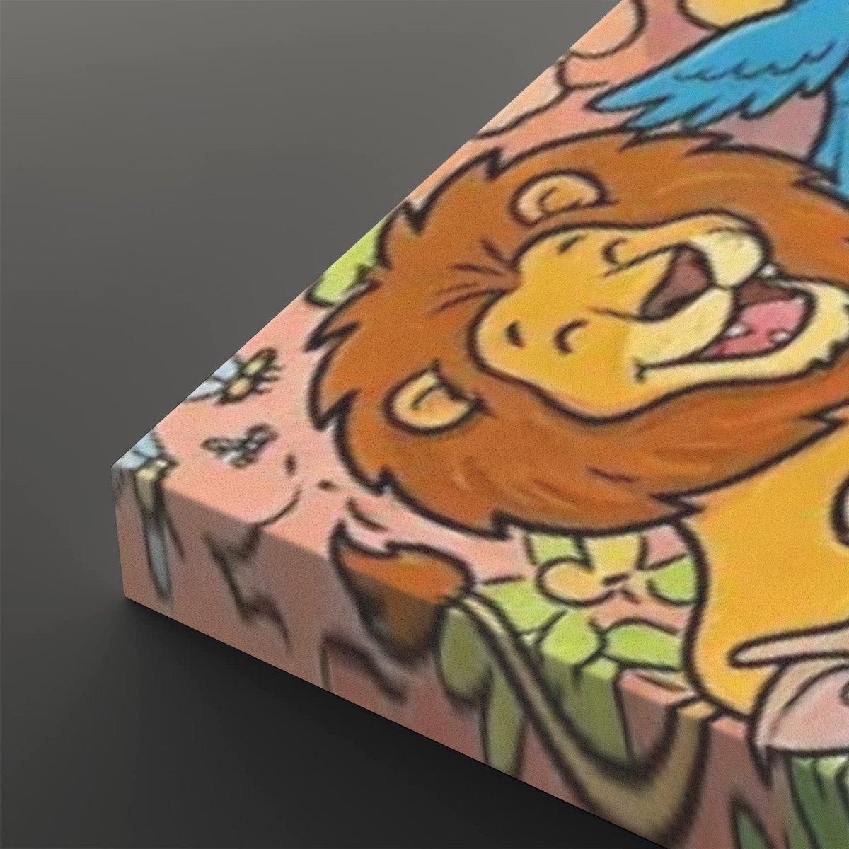 A close-up of a colorful illustrated product corner showing a cartoon lion face with a golden mane on a pink background, photographed against a dark gray studio backdrop.