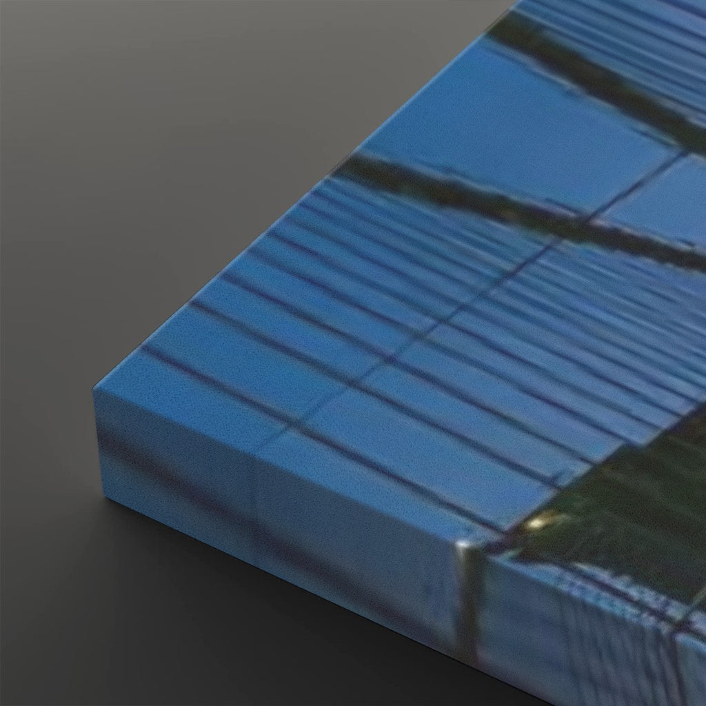A close-up of a rectangular canvas or print showing a blue-toned architectural scene with dark lines and a small patch of green, photographed against a dark gray background.
