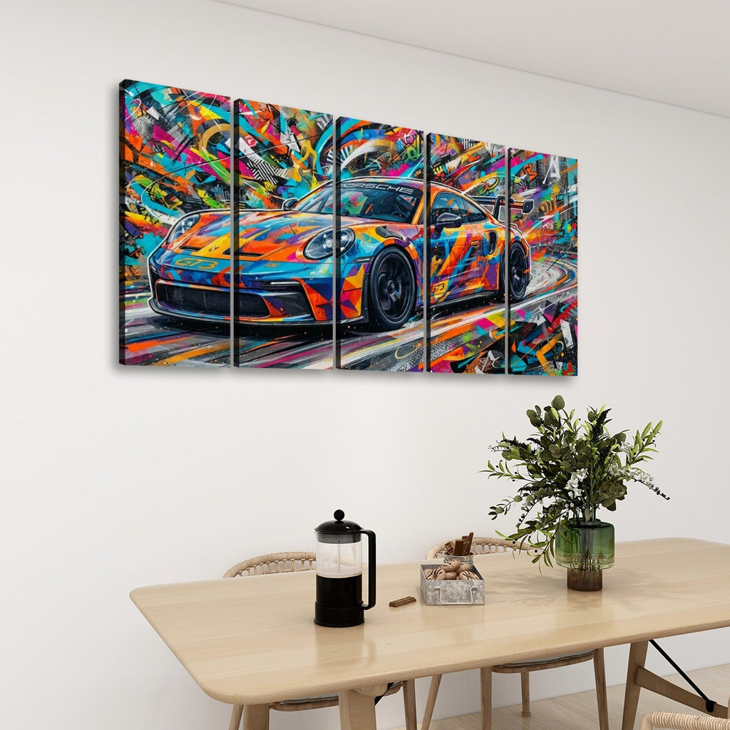 A 5-panel canvas wall art set depicting a colorful, graffiti-style painted sports 911 GT3 car, displayed on a white wall above a wooden dining table with a plant and French press.