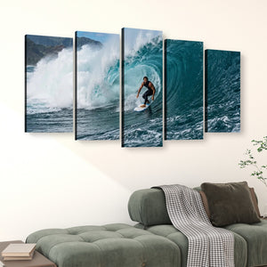 A five-panel canvas wall art set depicting a surfer riding a large blue wave, displayed above a green sofa in a modern living room setting.