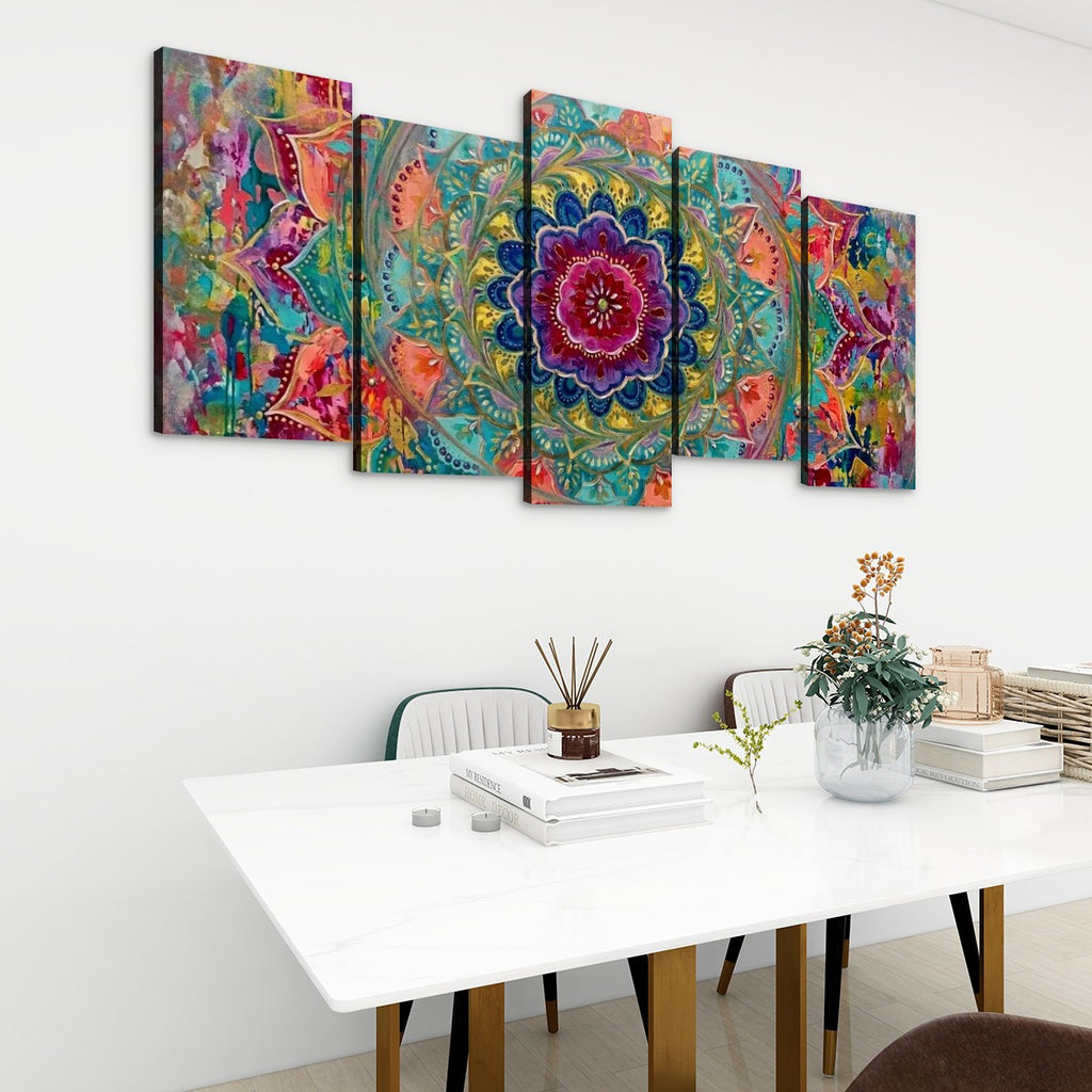 A 5-panel canvas wall art set featuring a vibrant, colorful abstract mandala design, displayed on a white wall above a modern white dining table with books and a vase.