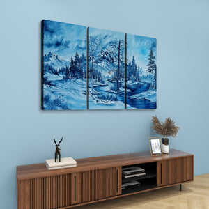A three-panel canvas wall art set depicting a snowy mountain landscape in shades of blue, hung above a wooden console table in a styled room setting.