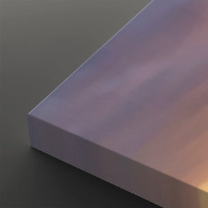 A close-up of a rectangular panel or board with a smooth, matte finish, showing a gradient of lavender, purple, and soft pink tones under warm light, set against a dark gray background.