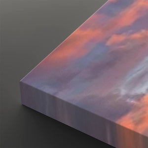 A close-up of a rectangular canvas or panel with a printed sky scene in soft purple, pink, and peach tones, shown against a dark gray background.