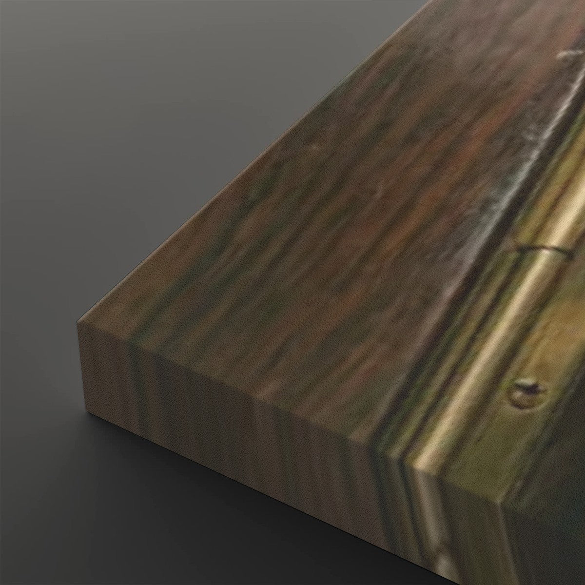 A close-up of a rectangular wooden board or panel with visible wood grain, showing a mix of brown, tan, and olive tones, photographed on a dark gray background.