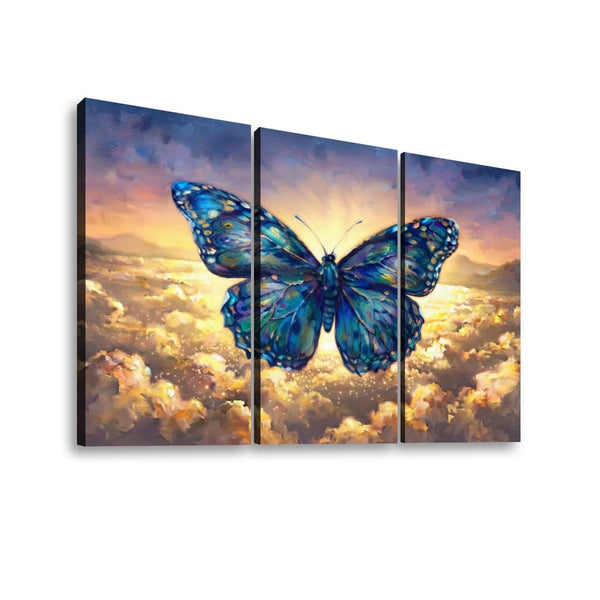 Three-panel canvas wall art showing a large blue butterfly over a glowing mountain landscape and clouds, photographed against a light gray background.