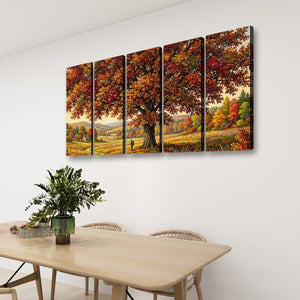 A four-panel canvas wall art set depicting a large autumn tree in a colorful forest landscape, displayed on a white wall above a light wood dining table with chairs and a green plant.