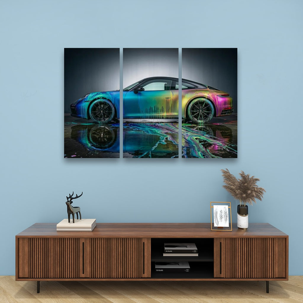 A three-panel canvas wall art print depicting a colorful sports car with a reflective watercolor effect, displayed on a light blue wall above a wooden console table with decorative items.