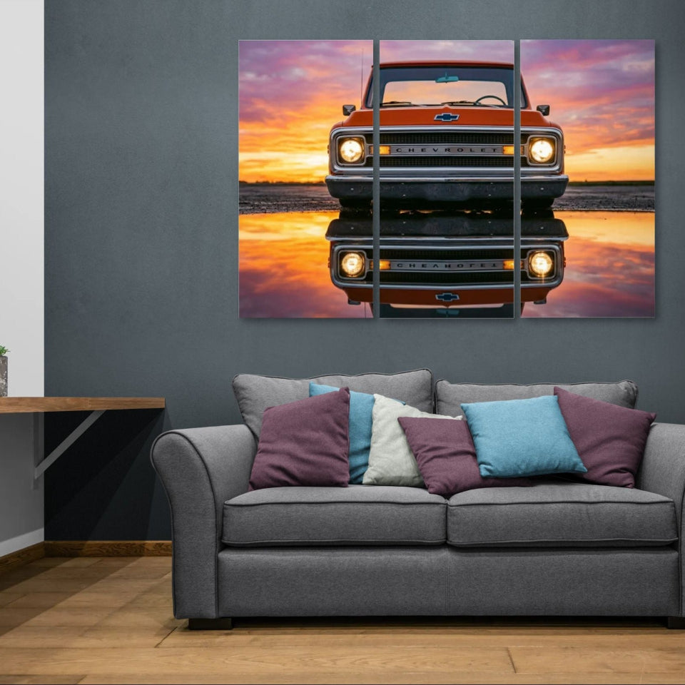 Gray sofa with colorful pillows in a room with a large wall art of a truck at sunset.