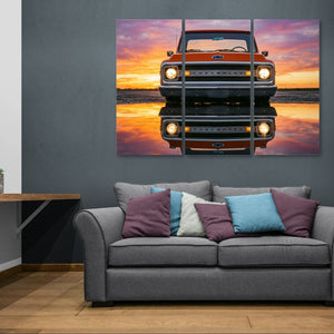 Gray sofa with colorful pillows in a room with a large wall art of a truck at sunset.