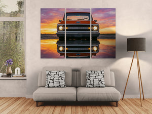 Living room with a large wall art of a vintage 1970 Chevrolet C10 truck at sunset, a gray sofa with patterned pillows, and a lamp.