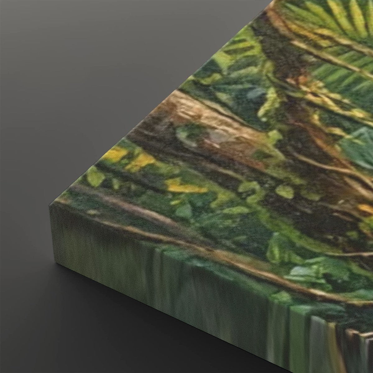 A close-up of a square canvas or panel art print showing a detailed tropical jungle scene with green leaves, brown branches, and yellow highlights, photographed against a dark gray background.