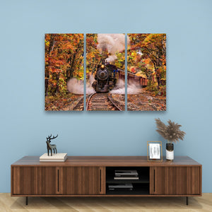 A three-panel canvas wall art print depicting a steam train traveling through an autumn forest, displayed on a light blue wall above a wooden console table with decorative items.