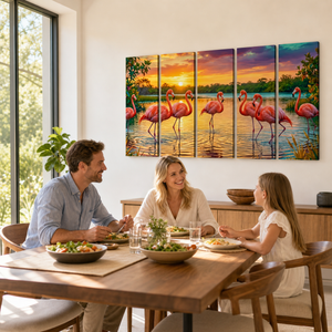 A five-panel canvas wall art set depicting pink flamingos at sunset is displayed above a dining table where a family is seated and eating. The artwork features vibrant sunset colors and flamingo details, shown in a warm, modern dining room setting.