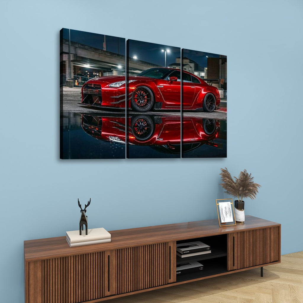 A three-panel canvas wall art print showing a red  Nissan GTR R35  sports car reflected in water, displayed above a wooden console table against a light blue wall.