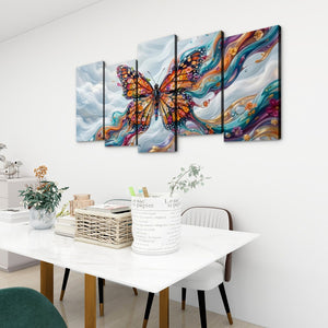 A five-panel canvas wall art set depicting a colorful Monarch butterfly over swirling blue, white, and orange clouds, displayed above a dining table in a modern room setting.