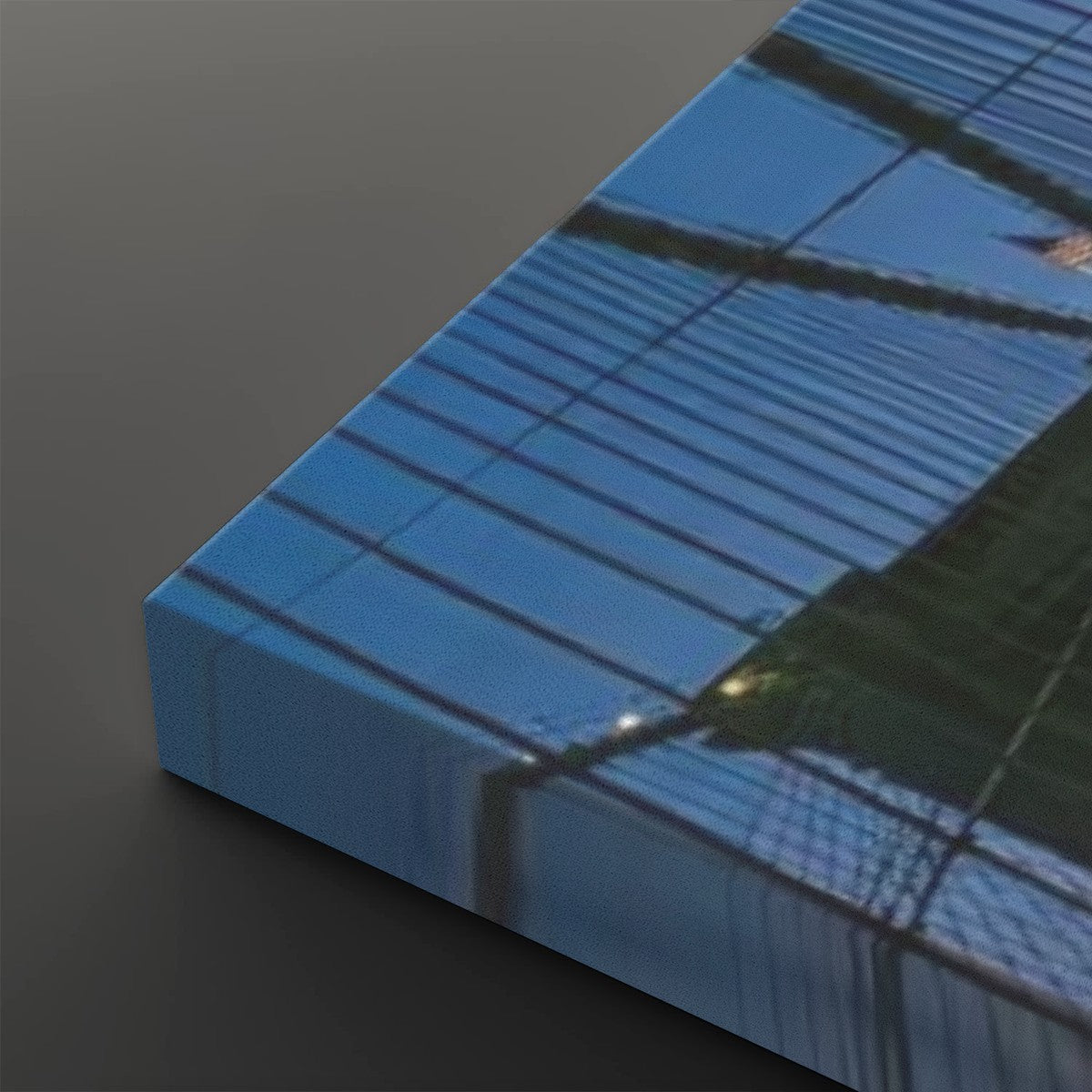 A close-up of a rectangular canvas or print showing an abstract blue and black grid-like reflection pattern, photographed on a dark gray background.