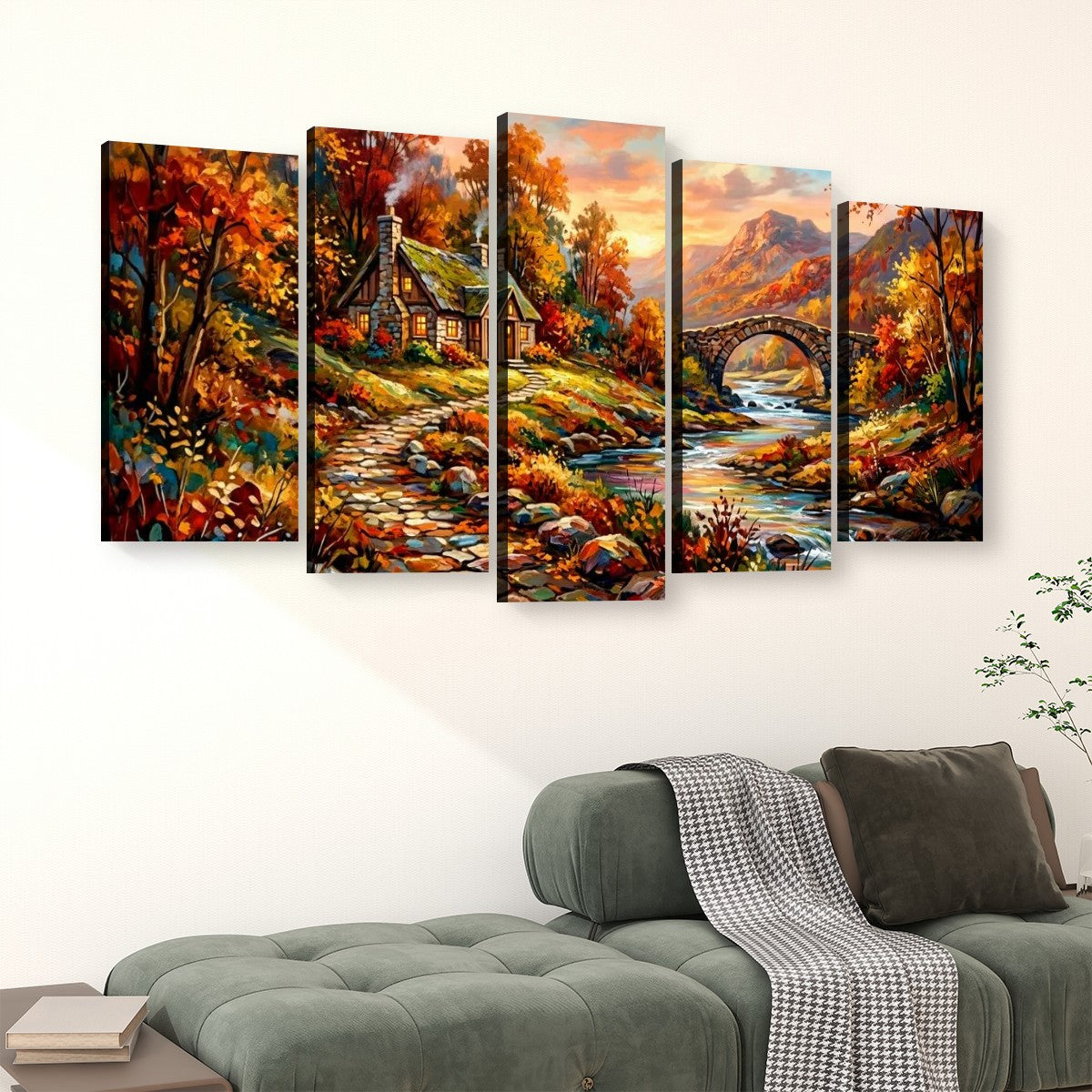 A five-panel canvas wall art set depicting a colorful autumn landscape with a cottage, bridge, river, and mountains, displayed above a green sofa in a living room setting.