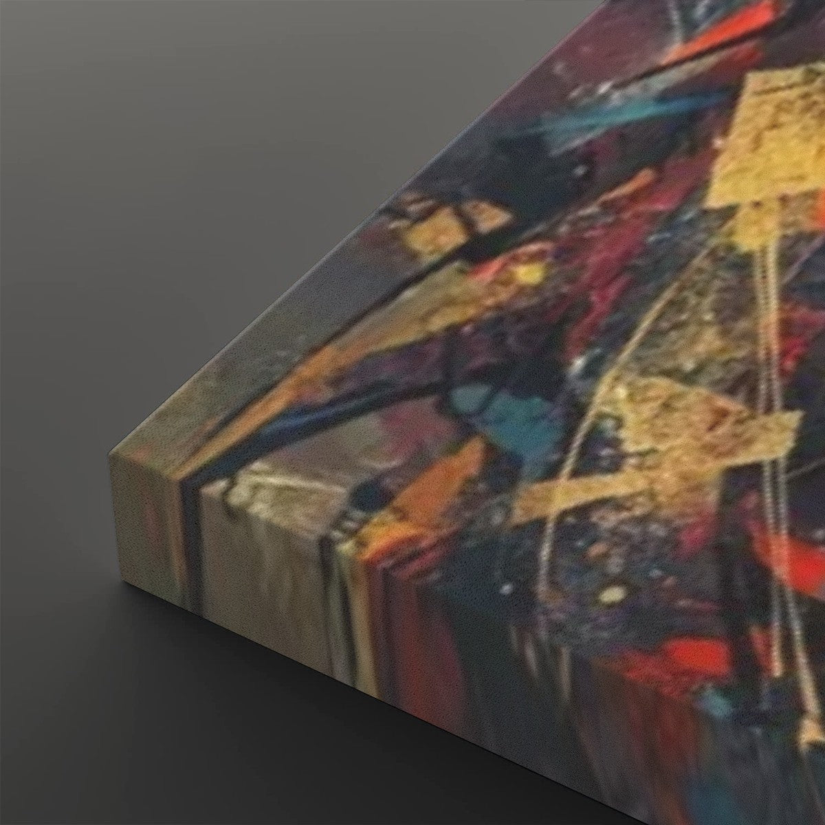 Abstract canvas wall art shown at an angle, featuring a multicolor paint-splattered design with red, blue, gold, black, and beige tones on a dark gray background.