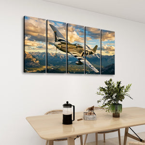 A five-panel canvas wall art set depicting a vintage military airplane flying over mountains under a dramatic cloudy sky, displayed on a white wall above a dining table with chairs and a plant.