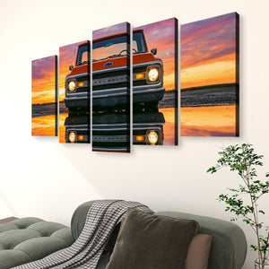 A five-panel canvas wall art set depicting a vintage red pickup truck facing forward on a reflective wet road at sunset, displayed above a green sofa in a living room setting.