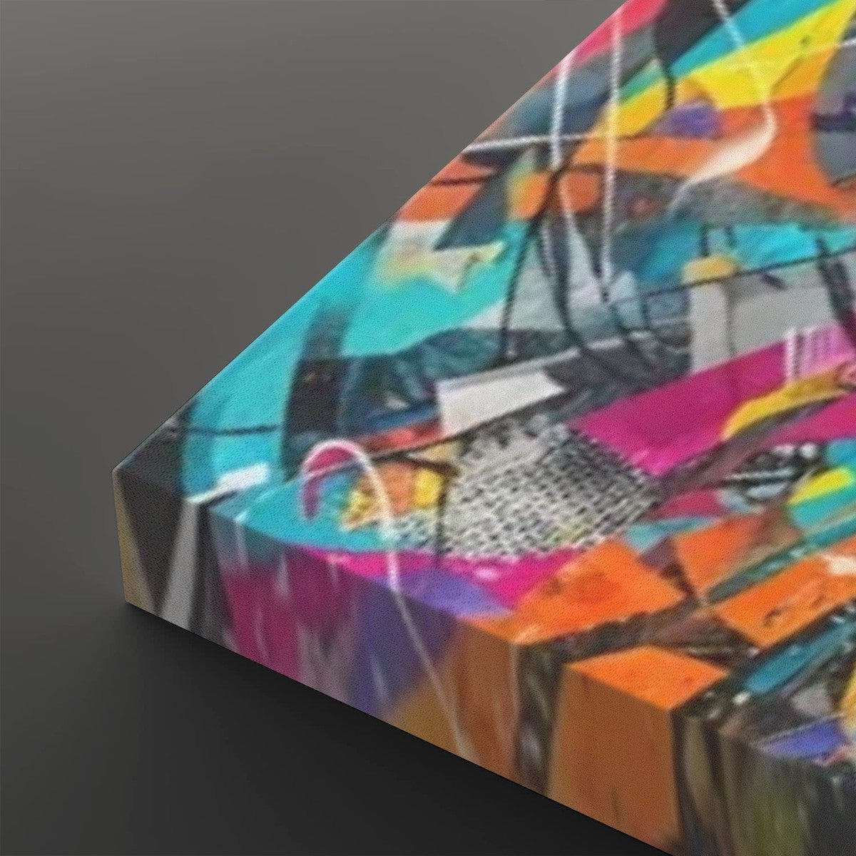Abstract canvas wall art featuring a vibrant multicolor graffiti-style design with bright turquoise, pink, orange, yellow, purple, black, and white brushstrokes, shown at an angle on a dark gray background.