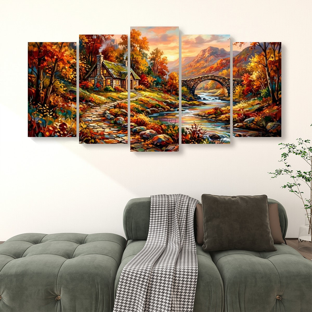 A five-panel canvas wall art set depicting a colorful autumn landscape with a cottage, bridge, river, and mountains, displayed above a green sofa in a living room setting.