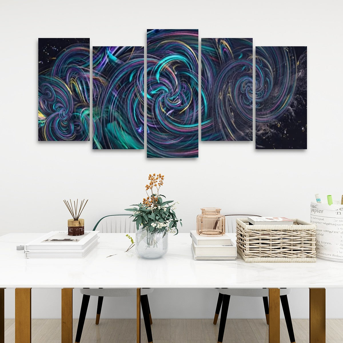 A five-panel canvas wall art set featuring an abstract swirling cosmic design in vibrant teal, purple, and black, displayed on a white wall above a styled white table with books, a vase, and a basket.