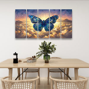 A five-panel canvas wall art set featuring a large blue butterfly over a dramatic sunset sky with clouds, displayed above a dining table in a modern room setting.
