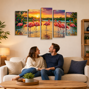 A five-panel canvas wall art set depicting pink flamingos at sunset over water, displayed above a couple sitting on a beige sofa in a modern living room setting.