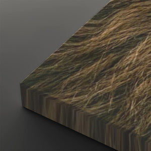 A close-up angled view of a rectangular panel or board with a realistic brown and tan grass-like texture on its top surface, shown against a dark gray background.