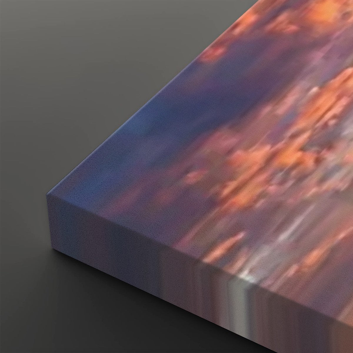 A close-up of a rectangular canvas or print showing an abstract landscape-like scene with flowing bands of blue, purple, orange, and pink, photographed on a dark gray background.