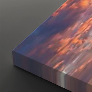 A close-up of a rectangular canvas or print showing an abstract landscape-like scene with flowing bands of blue, purple, orange, and pink, photographed on a dark gray background.