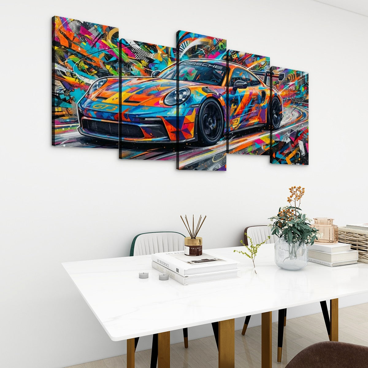 A 5-panel canvas wall art set depicting a colorful, abstract Porsche 911 sports car, displayed on a white wall above a modern dining table with books and a vase.