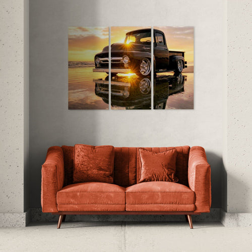 Triptych wall art of a  1956 Ford  F-100 classic truck at sunset over water, displayed above a red sofa.