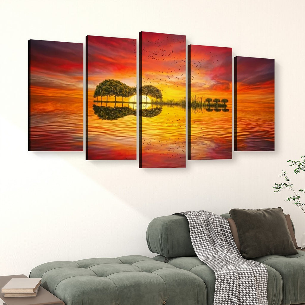 A 5-panel canvas wall art set depicting a vibrant sunset over water with tree reflections, displayed above a green sofa in a modern living room setting.