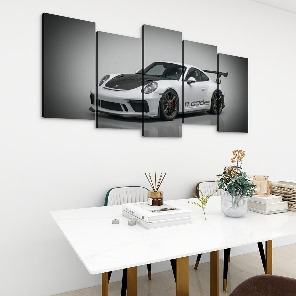 A 5-panel canvas wall art set depicting a black and white Porsche 911 GT3, displayed in a modern living room setting above a white dining table.