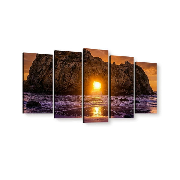 A five-panel canvas wall art set depicting a dramatic rocky coastline at sunset, with the sun low over the ocean and purple-toned waves in the foreground, shown against a plain white background.