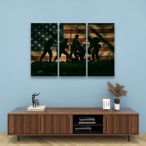 A three-panel canvas wall art set depicting silhouetted figures against a distressed American flag, displayed above a wooden media console against a light blue wall.