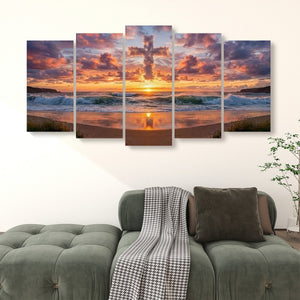 A five-panel canvas wall art set depicting a dramatic sunset over an ocean beach with a large cross silhouette in the sky, displayed above a green sofa in a living room setting.