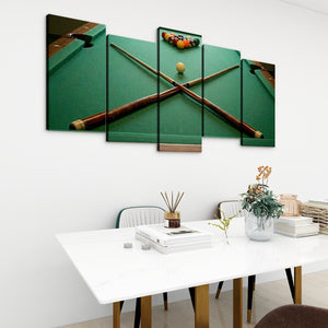 A 5-panel canvas wall art set depicting a green pool table with crossed pool cues and a billiard ball set, displayed on a white wall above a modern dining table.